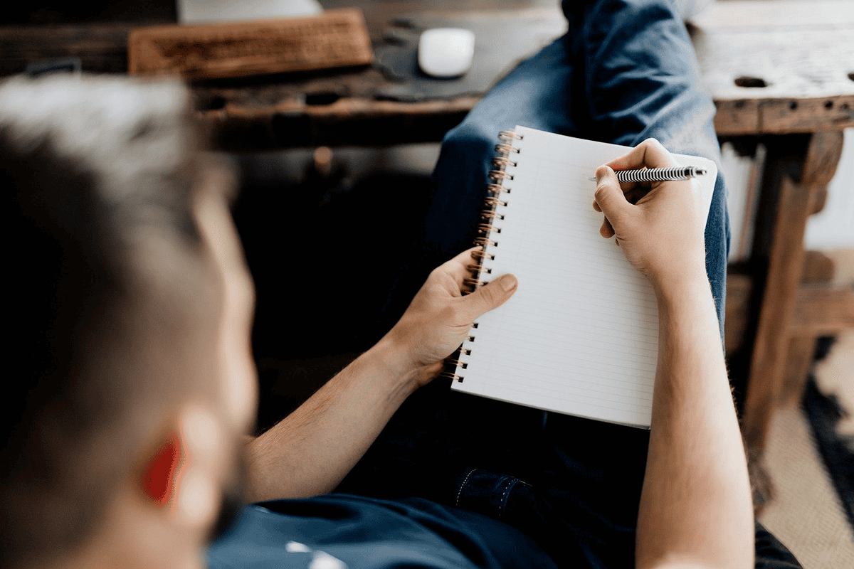 A man writing on a notepad about how to lose 30 pounds in a month. 