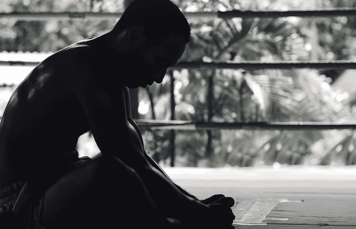 A black and white picture with a man sitting down on the floor after a workout. How to lose 30 pounds in 30 days. How to lose 30 pounds in a month.  