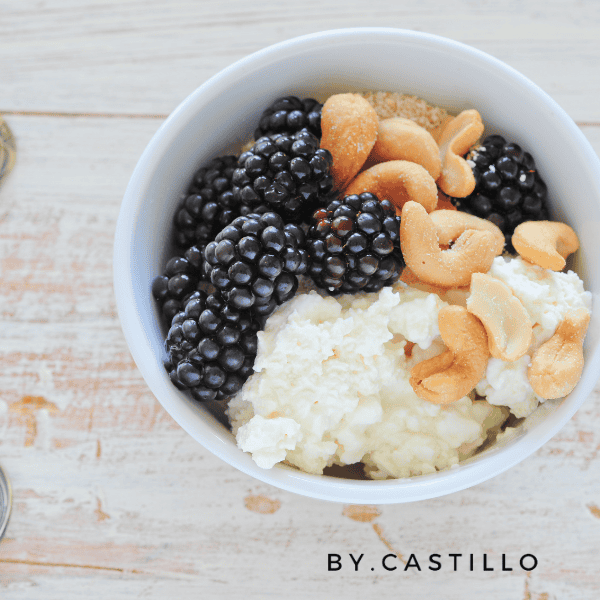 A picture of a white bowl with cottage cheese, black berries, and nuts. Lazy keto breakfast.